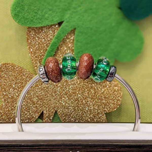 St. Paddy's Theme Bracelet Sterling sliver bangle bracelet with copper and green glass beads on display at jewelry store inside shopping mall..
